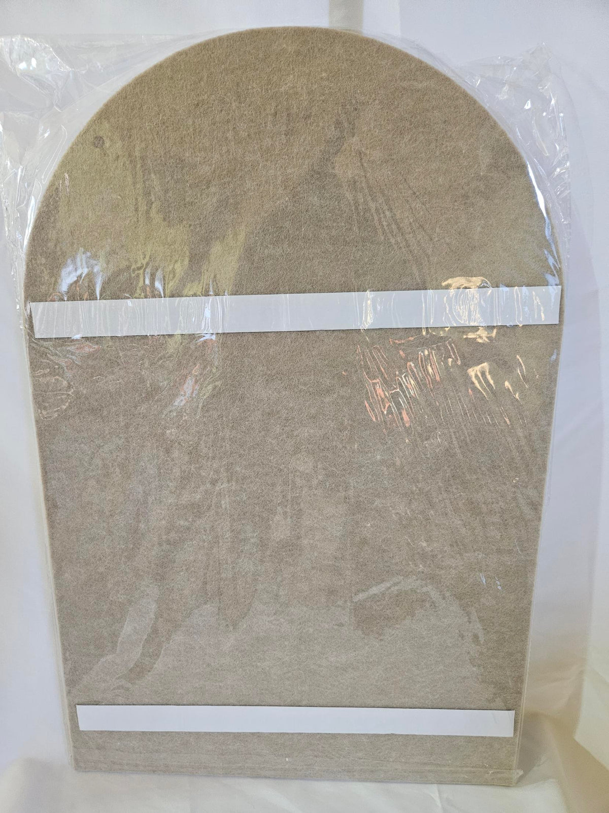 Bencheat camel felt bulletin board laid flat, arched top, adhesive strips on the back