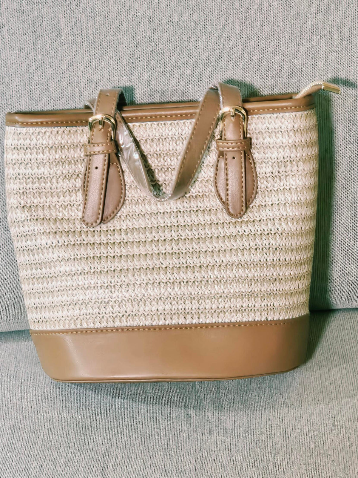 Woven straw tote bag angled view showing zip top